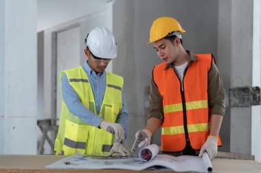 Mimar, bir inşaat sahasının ayrıntılı planlarını izliyor..