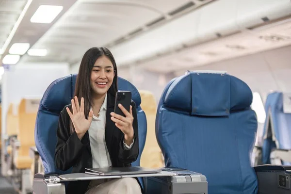 在飞机飞行期间 坐在靠窗的飞机座位上 拿着电话录像的年轻妇女坐在那里 — 图库照片