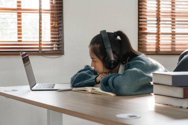 Sıkıcı Asyalı kız öğrenci ders çalışıyor, dizüstü bilgisayara bakıyor, sıkıcı online derslere katılıyor ya da konferanslara katılıyor. Sıkılmış tembel.
