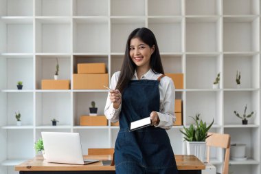 Girişim KOBİ küçük işletme girişimcisi serbest çalışan Asyalı kadın tablet ve boks kullanarak çevrimiçi müşterilere, çevrimiçi sme iş fikirlerine satış hazırlamak için siparişleri alır ve gözden geçirir.