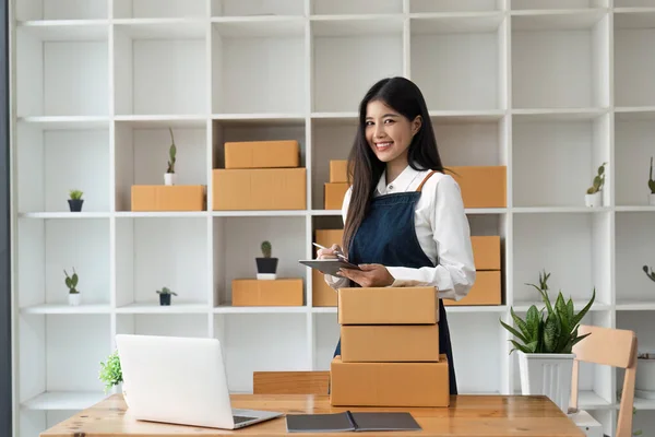 创办中小企业的亚洲自由女企业家利用平板电脑和盒子在网上接收和审查订单 准备打包销售给客户 网上羞辱商业理念 — 图库照片
