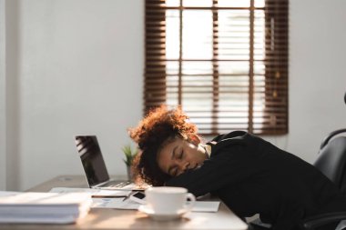 Uykulu ve yorgun genç siyahi iş kadını ya da ofis çalışanı kestiriyor ya da ofis masasında uyuyor..