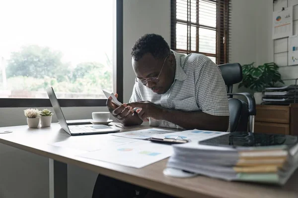 stock image African American man calculating using machine managing household finances at home, focused biracial male make calculations on calculator account taxes or expenses.