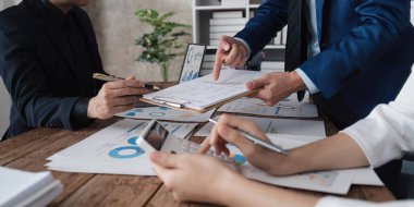 Ofisteki masadaki grafik verilerini analiz eden belgelerde istatistiksel iş kar büyüme oranını hesaplamak için hesap makinesi kullanan bir iş ekibi..