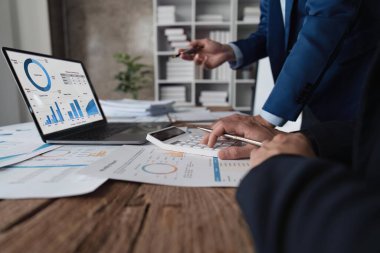 Ofisteki masadaki grafik verilerini analiz eden belgelerde istatistiksel iş kar büyüme oranını hesaplamak için hesap makinesi kullanan bir iş ekibi..