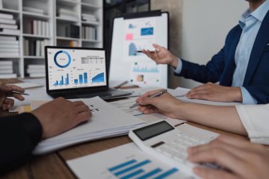 Ofisteki masadaki grafik verilerini analiz eden belgelerde istatistiksel iş kar büyüme oranını hesaplamak için hesap makinesi kullanan bir iş ekibi..