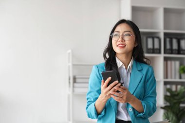 Ofiste akıllı telefon kullanan güzel bir iş kadını..