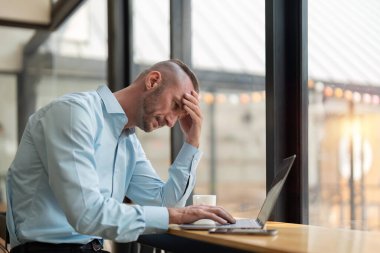 Ofiste oturan stresli bir iş adamı. Yorgun ve çok çalışan bir ofis çalışanı. Dizüstü bilgisayarla çalışan stresli genç adamlar..