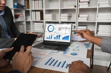 İş ekibi gelir tablolarını ve grafiklerini dizüstü bilgisayarla analiz ediyor. İş analizi ve strateji kavramı.