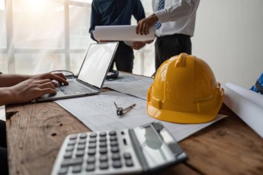 Proje inşaatını bildirmek için toplanan mühendisler dizüstü bilgisayar ekranında.