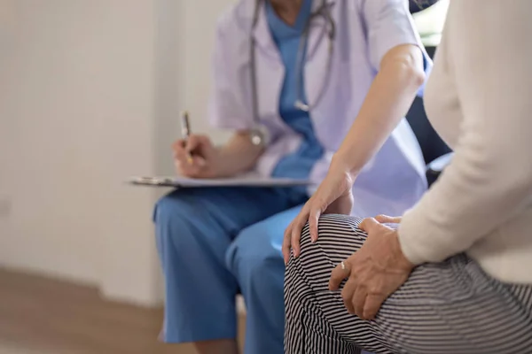 Mujer Doctora Sosteniendo Rodilla Mirando Una Paciente Anciana Mientras Explica —  Fotos de Stock