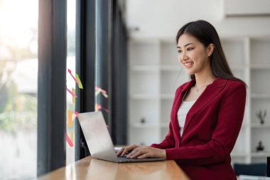 İş kadını laptopla çalışıyor, ofisteki renkli yapışkan kağıtlara notlar yazıyor..