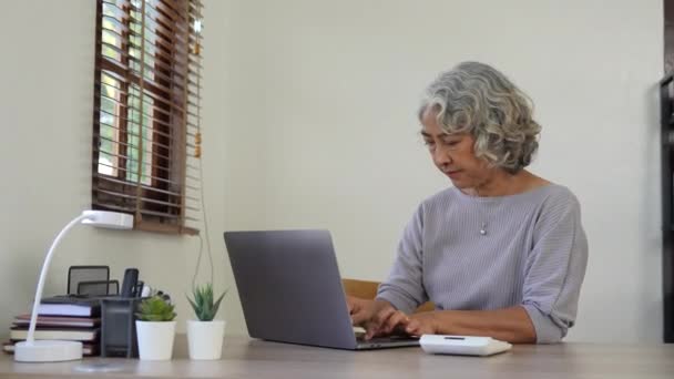 高齢者の女性は 計算し 書き込み オンラインで請求書を支払い 自宅から働く財務報告書を準備します 成熟した女性に焦点を当て 財政管理で忙しい会計の仕事をする — ストック動画