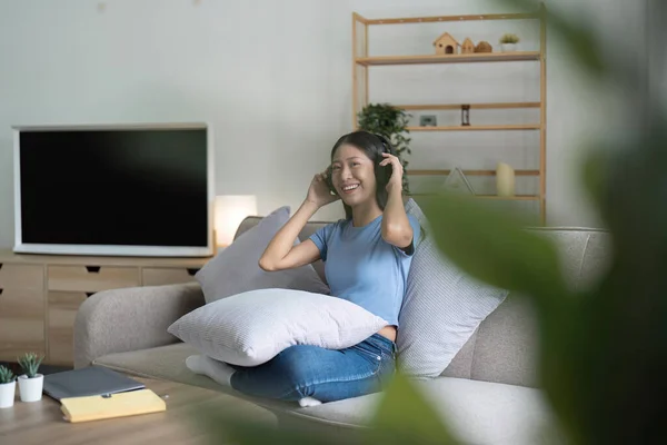 Asyalı Genç Bir Kadın Evdeki Kanepede Dinlenirken Müzik Dinliyor — Stok fotoğraf
