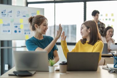 Modern dizüstü bilgisayarı olan genç Asyalı kadın, projeyi başlattıktan sonra iş arkadaşına beş puan veriyor..