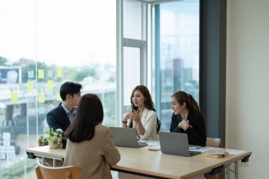Bir grup genç Asyalı yaratıcı iş adamı beyin fırtınası sunumu, ürün tanıtımının yol haritası, planlama, ofiste yeni bir strateji başlatma projesi hakkında tartışıyorlar..