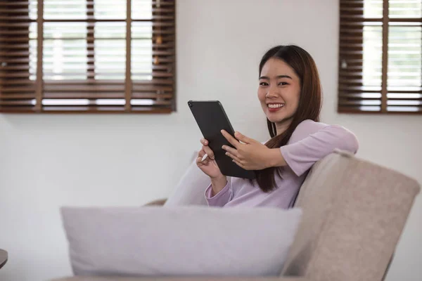 Bonita Atraente Jovem Mulher Asiática Sentada Sofá Cinza Usando Tablet — Fotografia de Stock