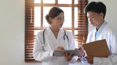 Tıbbi ekip iki yaşlı erkek ve genç kadın doktor beyaz önlüklü konuşmalar giyer, dijital tablet kullanır, tıp alanında ortaklık yapar, sağlık teknolojisi kullanır..