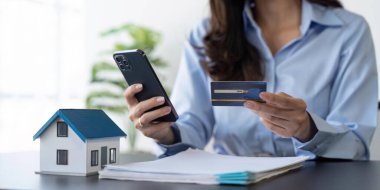 Kredi kartı tutan ve cep telefonu kullanan bir kadın. Çevrimiçi ödeme, internet bankacılığı, online alışveriş.