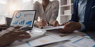 Belgeler üzerindeki istatistiksel iş kar büyüme oranını hesaplamak için bir hesap makinesi kullanan iş ekibi grafik verileri, bürodaki masa, takım çalışması süreci.