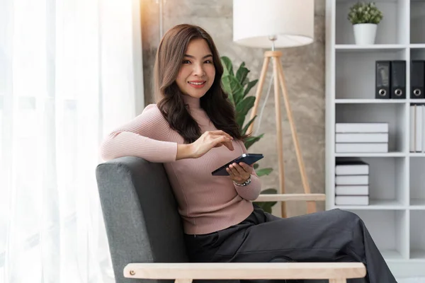 Gülümseyen Kadın Oturma Odasında Kanepede Oturup Akıllı Telefonuna Mesaj Atıyor — Stok fotoğraf