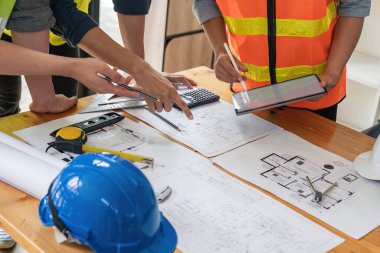 İnşaat mühendisleri proje planının taslağını ve tabletini kullanarak inşaat, mimarlık ve inşaat konseptinde beyin fırtınası ve birlikte çalışma yapıyorlar..