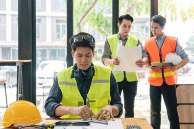 Mühendis planlar ve inşaat planları üzerinde çalışıyor. İnşaat mühendisleri inşaat çizimleri, inşaat mühendisliği ve inşaat sektörü kavramlarını hesaplar ve taslak yapar..