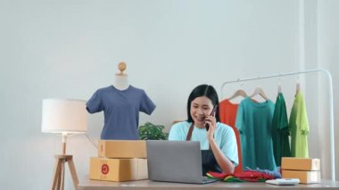 Bilgisayar kullanan, cep telefonuyla konuşan ve ürün stoklarını kontrol eden Asyalı güzel bir kadın..