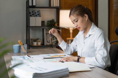 Muhasebeci genç Asyalı kadın dizüstü bilgisayar üzerinde çalışıyor ve evrak, vergi, takas, muhasebe ve evde mali danışman konsepti üzerinde çalışıyor..