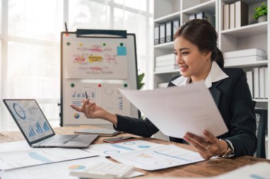 Muhasebeciler Asyalı iş kadını modern bir ofiste vergi danışmanı olarak çalışıyor. Hesap analizi raporu hazırla. Gayrimenkul yatırım bilgileri finansal ve vergi sistemi kavramları.