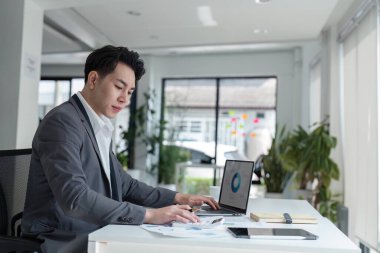 Genç iş adamı dizüstü bilgisayara bak harcamaları hesapla fatura vergilerini internette öde. Erkek şirket bütçesini yönetmekle meşgul, mali evrak işleriyle ilgileniyor..
