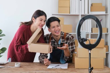 Genç çift cep telefonlarını canlı olarak çevrimiçi sosyal medyada kaydediyor ürünleri çiftler halinde satıyor, serbest çalışıyor, kendi işlerinde veya girişimcilerinde çalışıyor. E-ticaret, alışveriş konsepti.