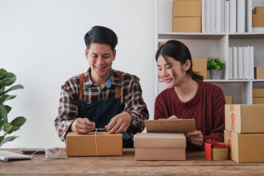 İşyerinde bilgisayarla çalışan küçük bir işletme sahibi. Serbest çalışan erkek ve kadın satıcı ürün siparişini kontrol eder, müşteriye mal teslimatı yapar. Online satış, e-ticaret.