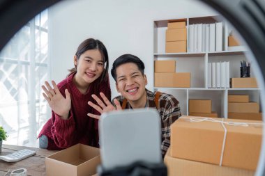 Genç çift cep telefonlarını canlı olarak çevrimiçi sosyal medyada kaydediyor ürünleri çiftler halinde satıyor, serbest çalışıyor, kendi işlerinde veya girişimcilerinde çalışıyor. E-ticaret, alışveriş konsepti.