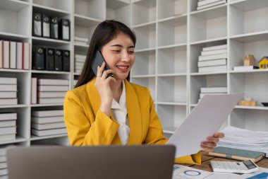 İş kadını telefonda konuşuyor ve ofiste belgelerle çalışıyor..