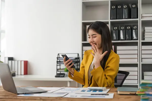 stock image Excited businesswoman winning after achievement reading a smart phone sitting in a desk at office.