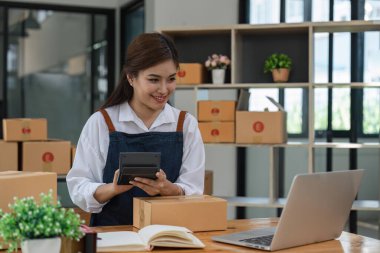 Küçük işletmeli bir kadın iş yerinde hesap makinesi kullanıyor. KOBİ 'yi başlat küçük işletme girişimcileri evde çevrimiçi kutularla çalışarak ekommerce paketleme satıyorlar.