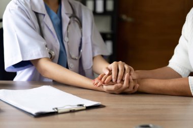 Doktorun eli, kıdemli kadın hastasına güven veriyor. Tıbbi etik ve güven kavramı.