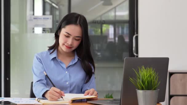 ペンやノートを持ったアジア系の女性を笑顔にするのはオフィスでの起業です — ストック動画