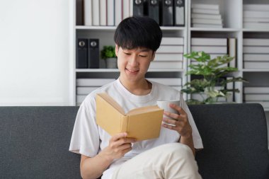 Fincan kahve okuma kitabı evde kanepe ile yakışıklı adam.