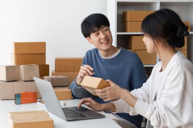 Evde çalışan Asyalı mutlu çiftin resmi. Online mağazalarında mutlu ve başarılılar. Serbest girişimcilik ve çevrimiçi iş dünyası kavramı.