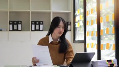 İnternette ofis masasında çalışan genç iş kadını tablet üzerinde yazıyor..