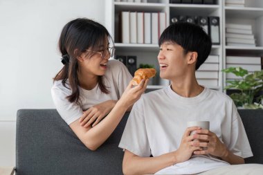 Genç çiftler tatillerini oturma odasında geçirirler. Genç adam rahat kıyafetler giyiyordu, yüzünü gösteriyordu, atıştırmalıkların tadından memnundu. Kanepede kruvasan yemek..