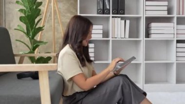 Mutlu kadın evde tablet kullanarak mesajlaşmayı gevşet.