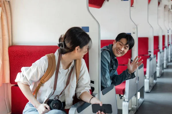 Przyjazny Młody Azjatycki Podróżnik Macha Ręką Witając Nowego Przyjaciela Podczas — Zdjęcie stockowe