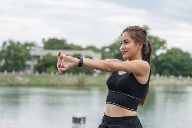 Kollarını açarak ısınan sağlıklı bir kadın. Asyalı koşucu kadın antrenmanı ve doğa parkında koşu seansı. Sağlıklı ve Yaşam Tarzı Konsepti.