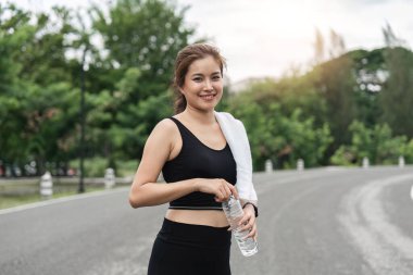 Koştuktan sonra su içen kadın. Spor kıyafetli güzel kızın portresi spor salonundan sonra dinleniyor, şişeden su içiyor..