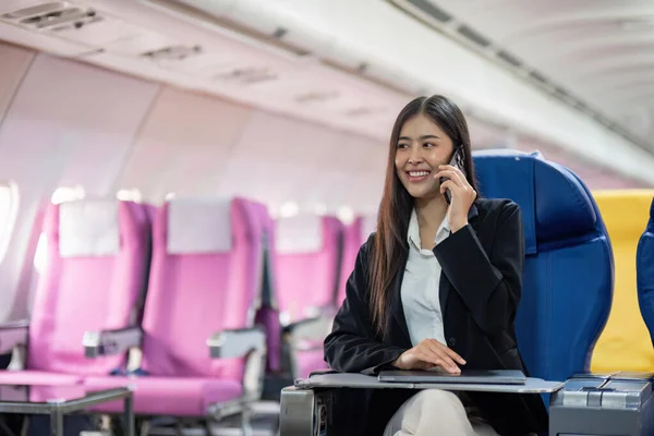 Young Asian woman sitting with phone on the aircraft during the flight in the airplane.