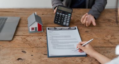 Emlakçı müşterilere örnek evler, ipotekli kredi sözleşmeleri veriyor. Kiralık bir ev alıp satmak için bir sözleşme yap. ve ev sigortası sözleşmeleri, ev kredisi konseptleri.