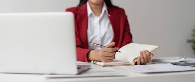 İş kadınları bilgisayarda çalışır ve ofis hesaplarını hesaplamak için kalemle not defterine yazarlar..